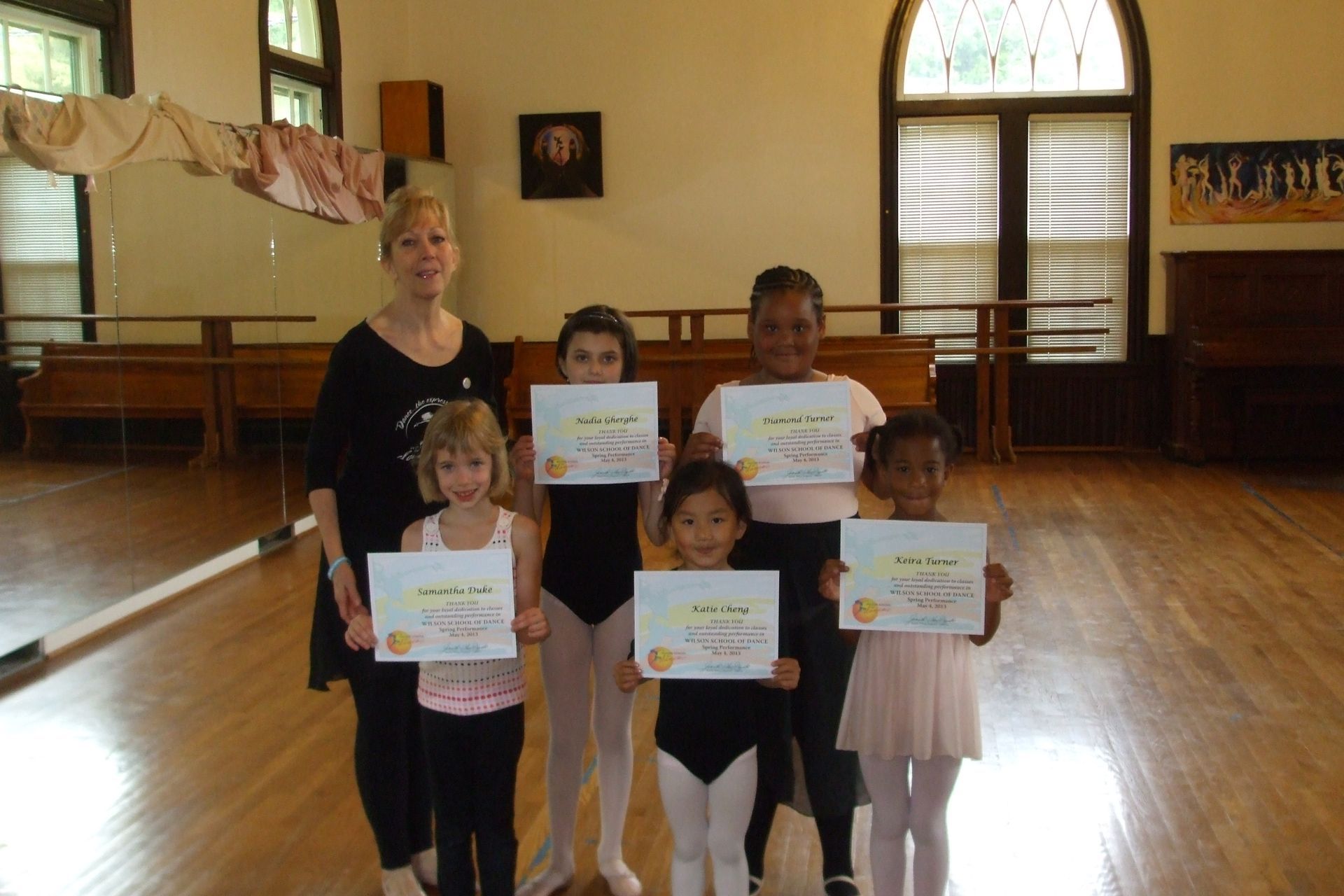 a group of young girls holding up certificates in a dance studio