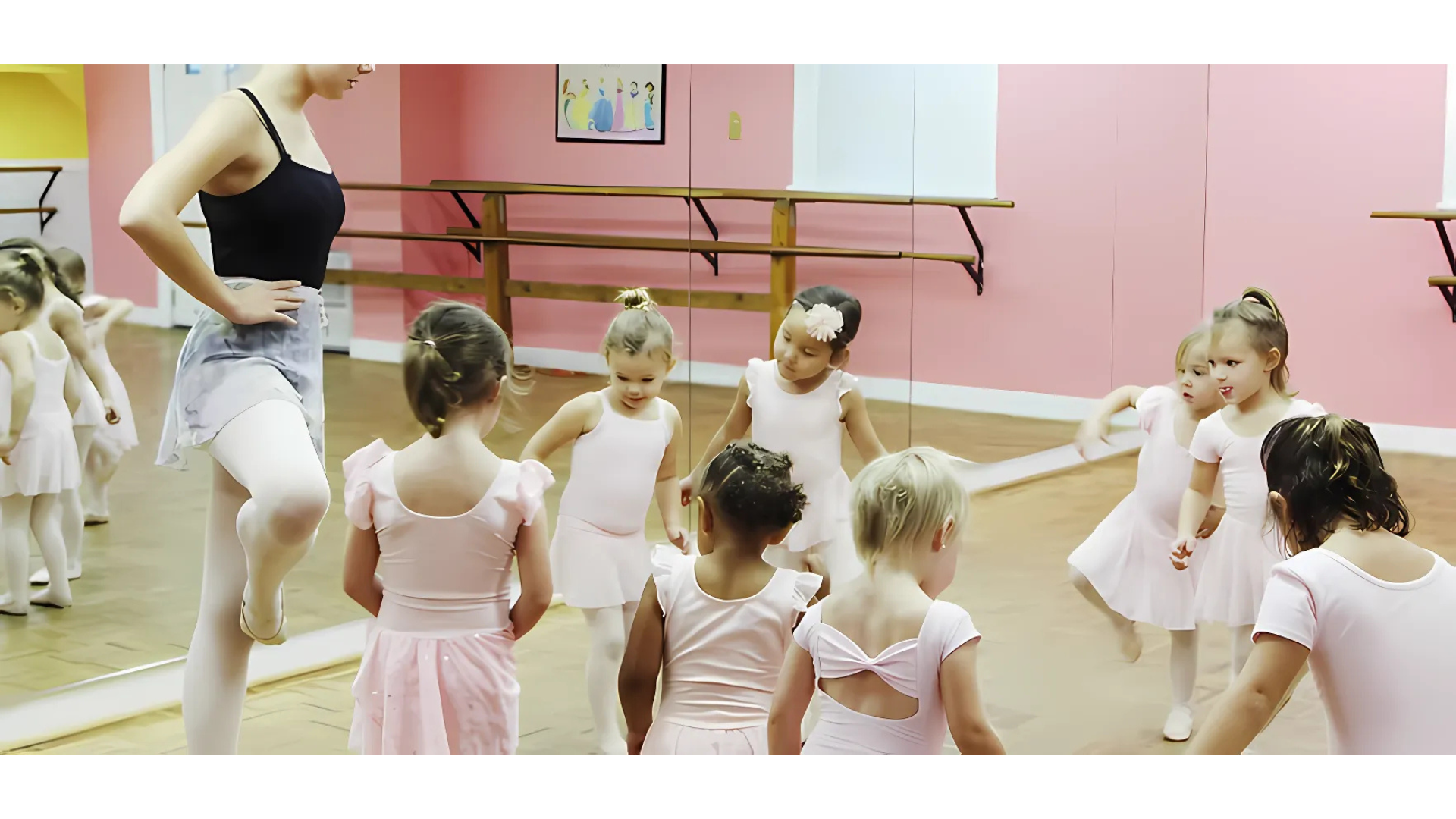A group of young girls are standing in front of a mirror in a dance studio.