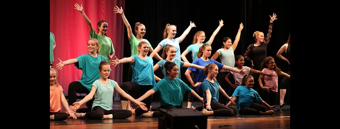 a group of young girls are dancing on a stage .