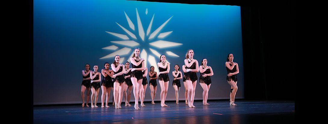 a group of dancers are standing on a stage in front of a blue light .