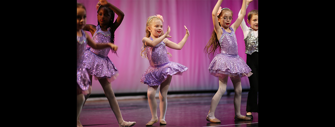a group of young girls are dancing on a stage .