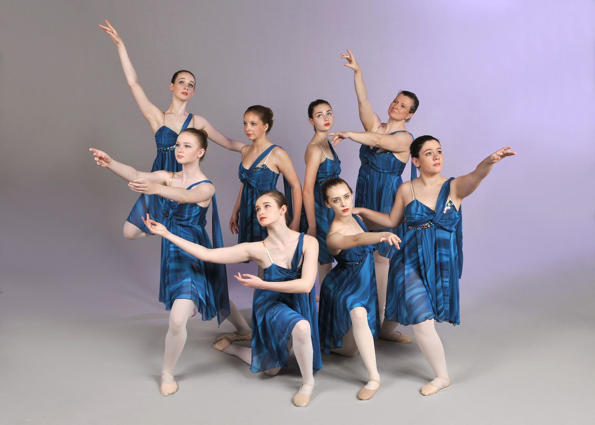 a group of young women in blue dresses are dancing together .