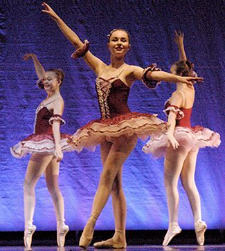 three ballerinas are dancing on a stage with their arms outstretched