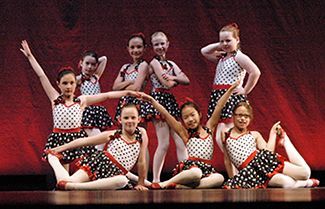a group of young girls are dancing on a stage .