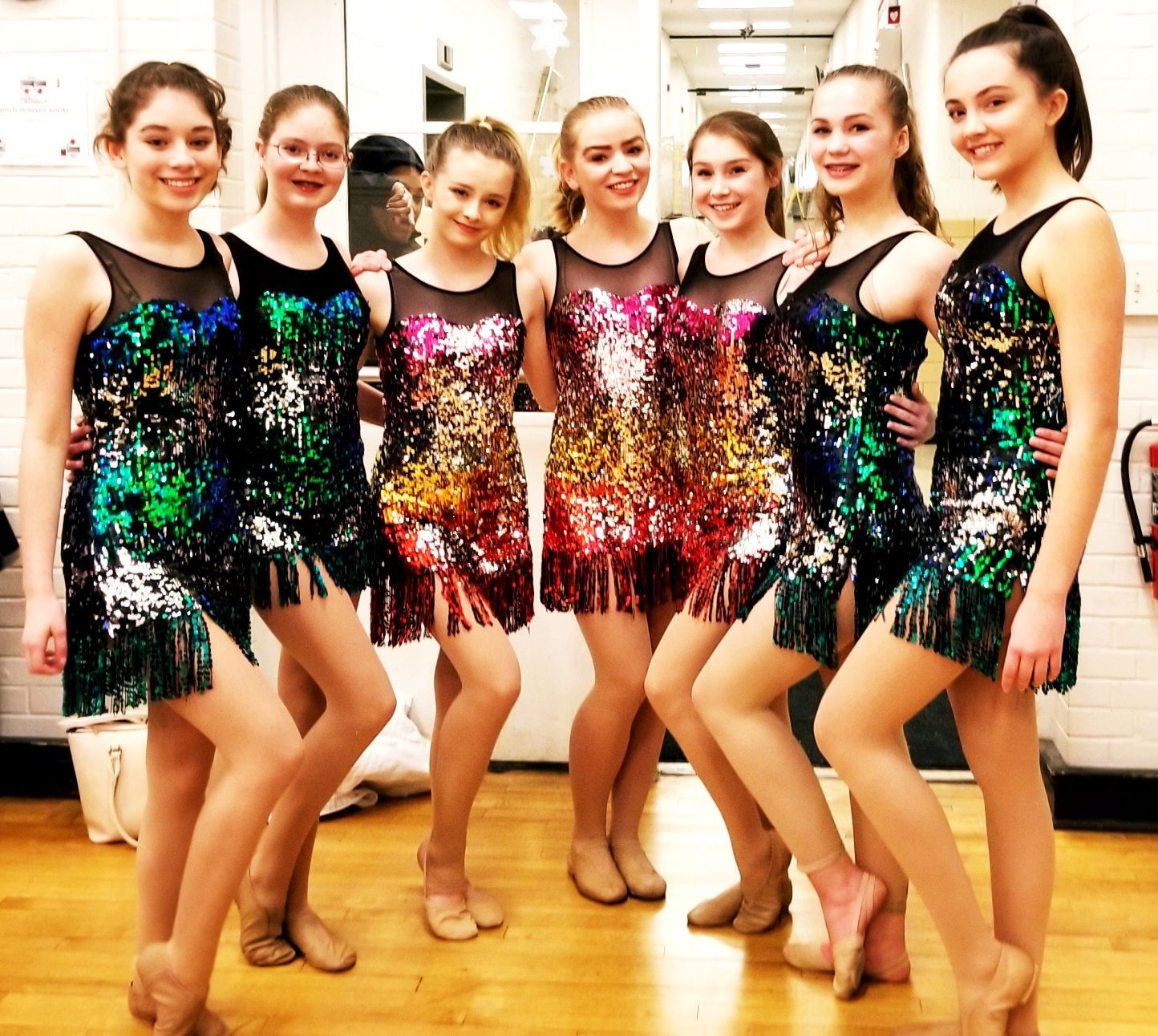 a group of young women in sequined dresses pose for a picture