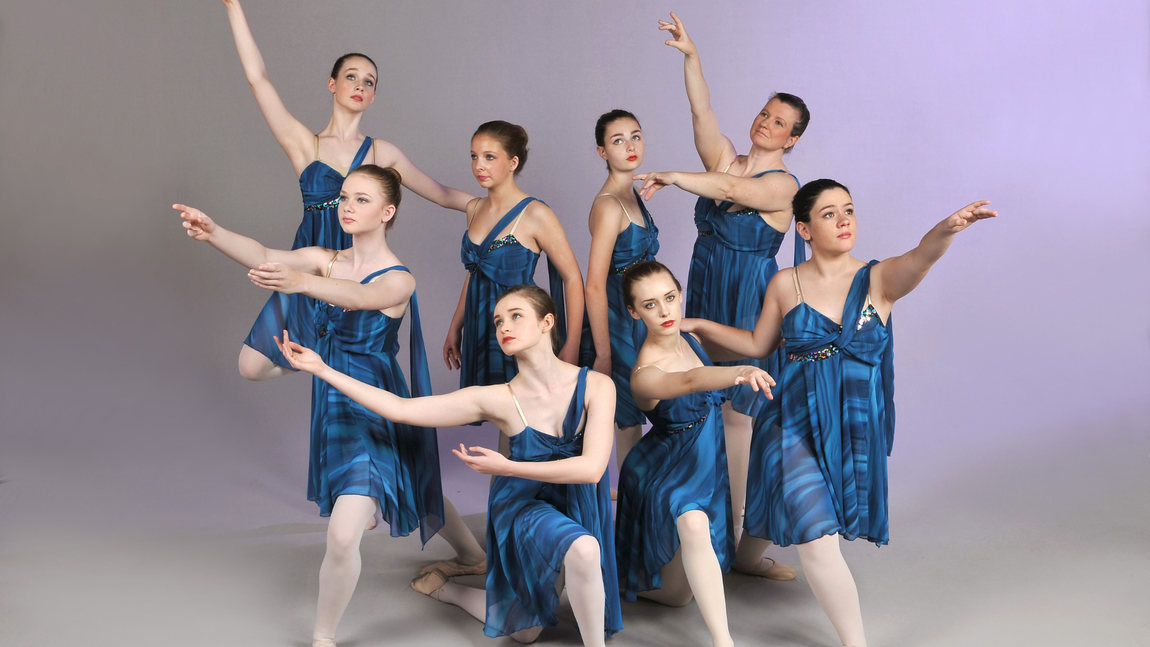 a group of young women are dancing together in blue dresses .