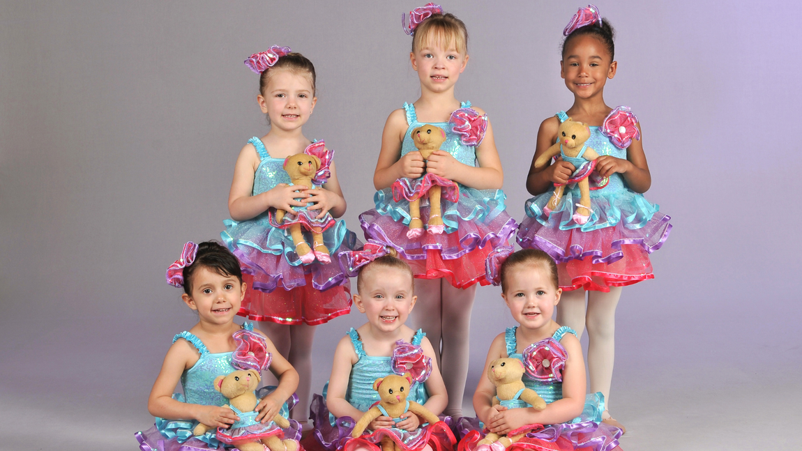 a group of young girls are posing for a picture while holding teddy bears .