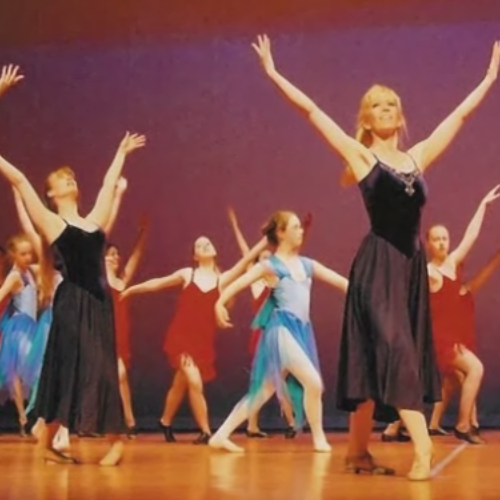 a group of women are dancing on a stage with their arms outstretched