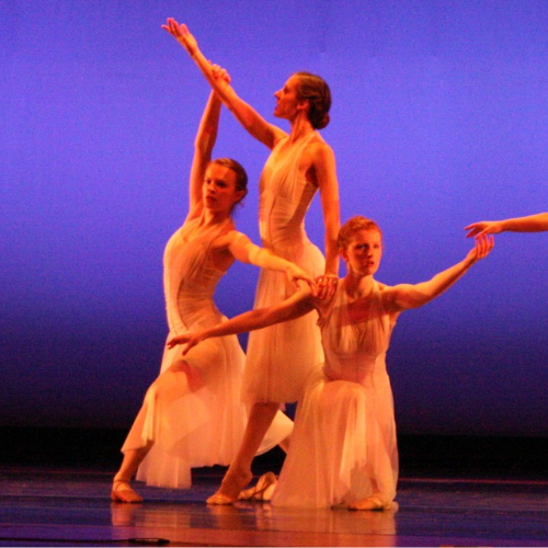 a group of women in white dresses are dancing on a stage