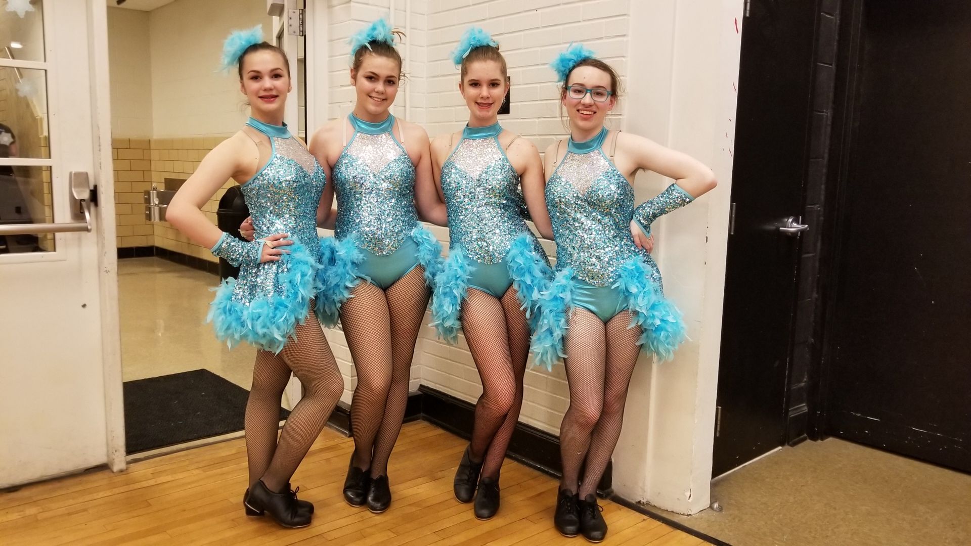 a group of young women in blue dresses are standing next to each other in a room .