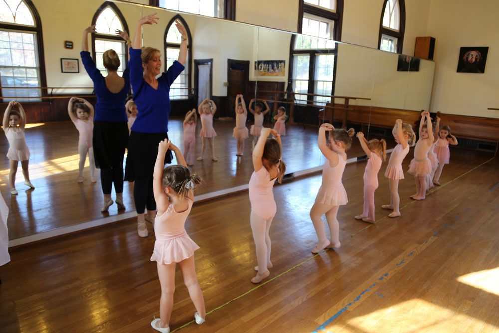 A dance instructor is teaching a young class of balerians how to dance