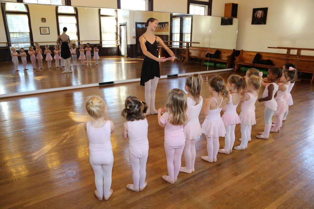 a group of young girls are standing in front of a mirror in a dance studio .
