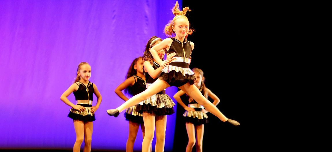 a group of young girls are dancing on a stage .