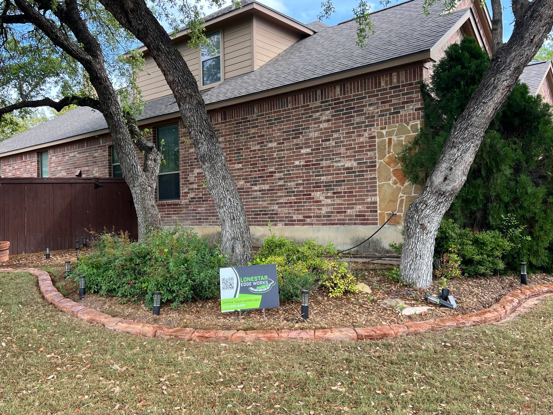 A brick house with a sign in front of it.