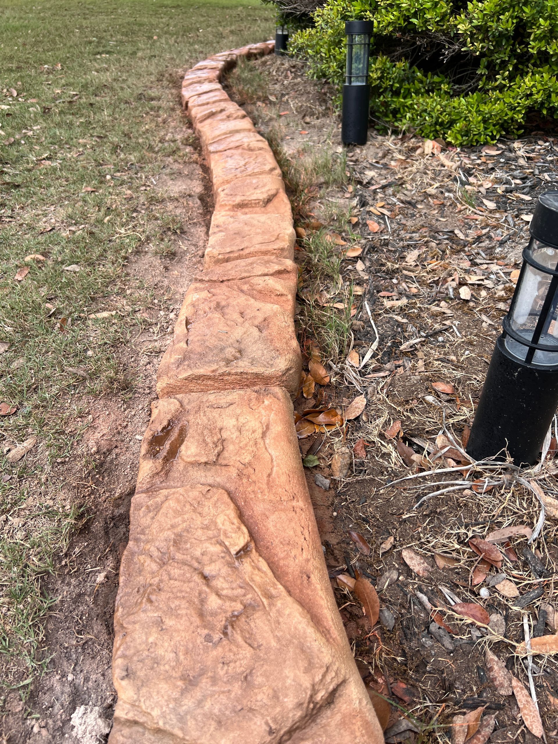 A stone walkway in a yard next to a lamp post.