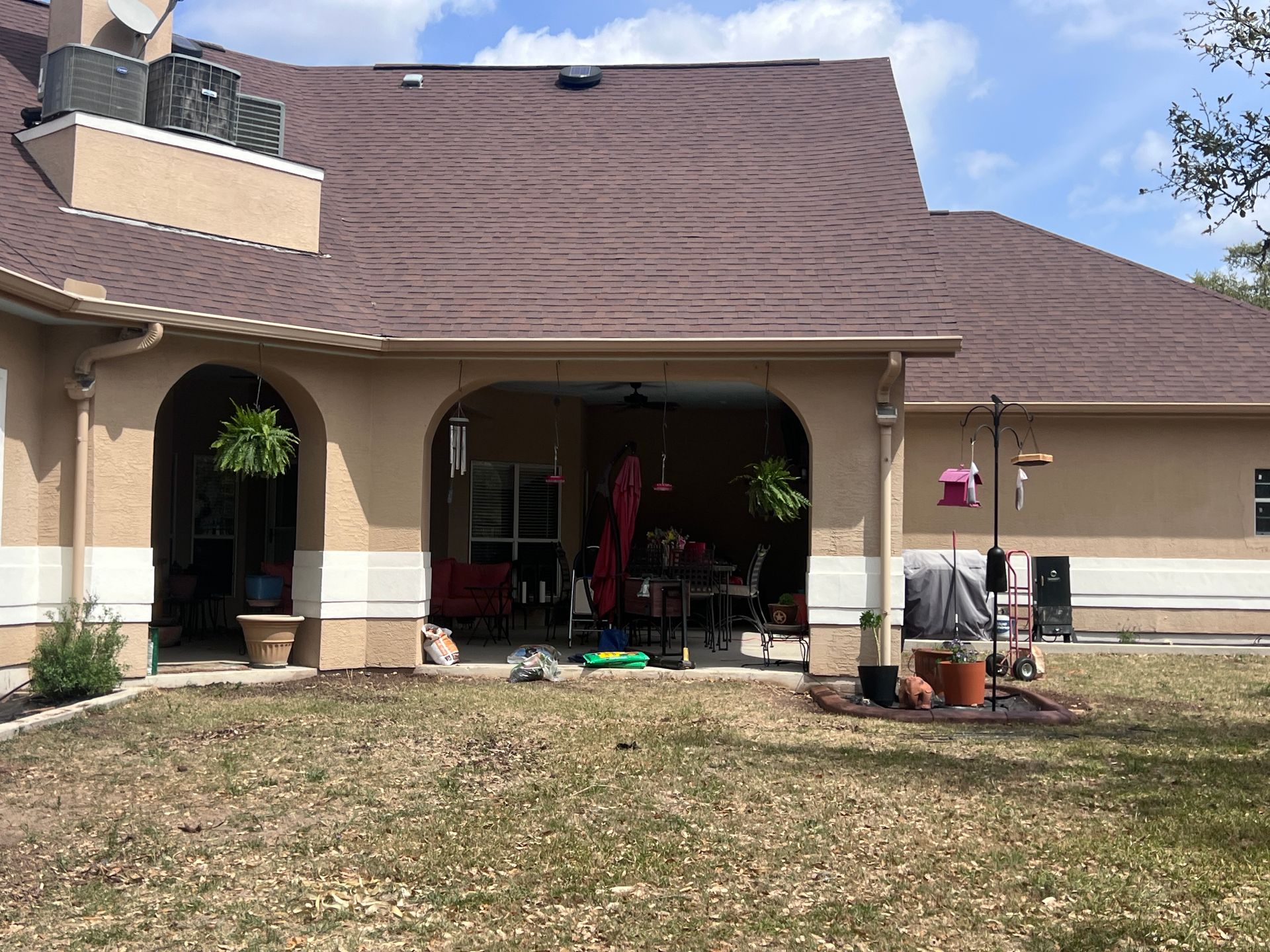A large house with a covered patio and a large yard.