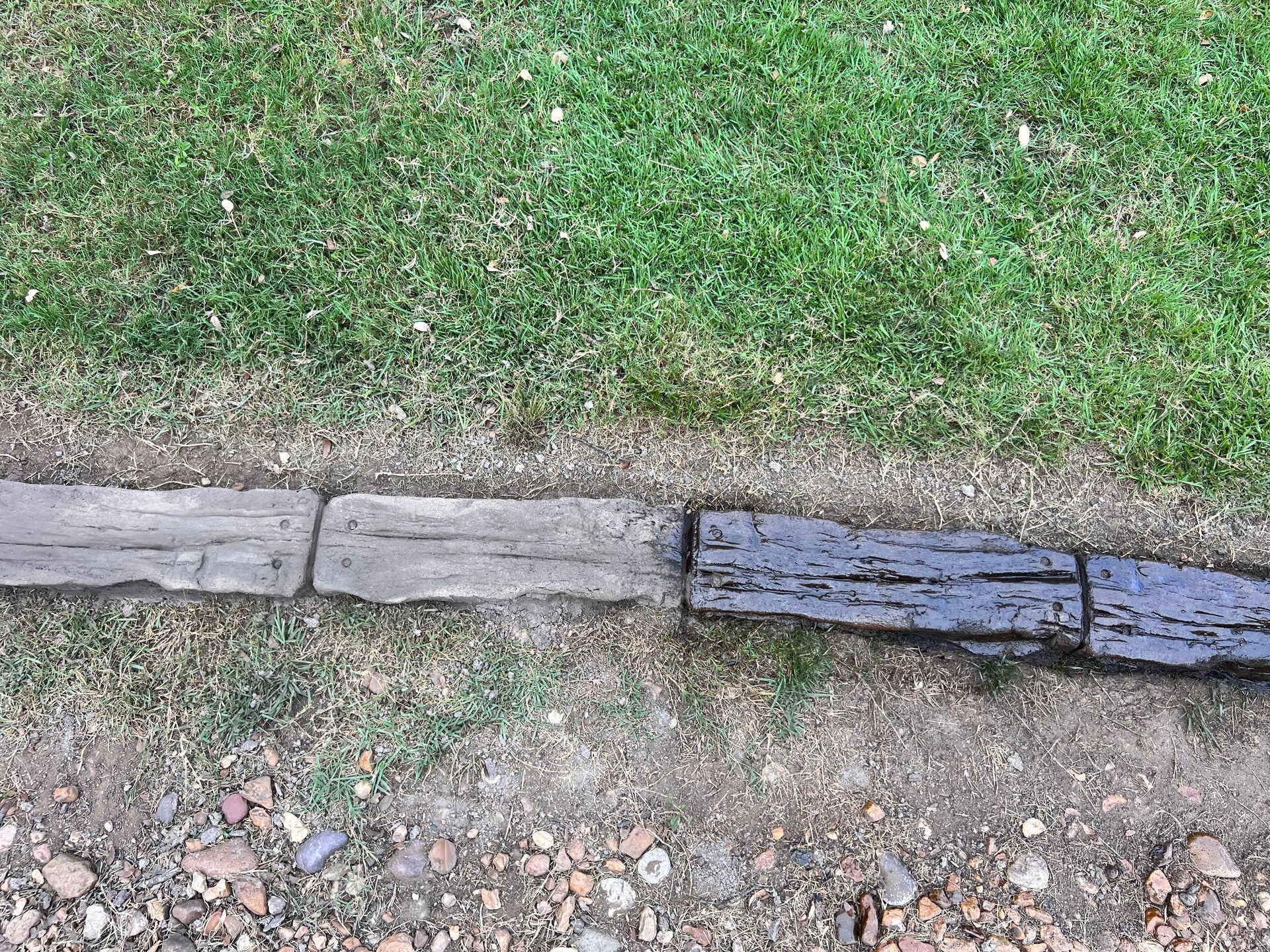 A wooden edging is sitting next to a lush green lawn.