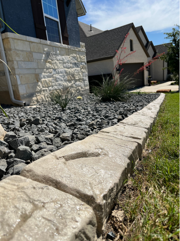 A stone walkway leading to a house with rocks in front of it.