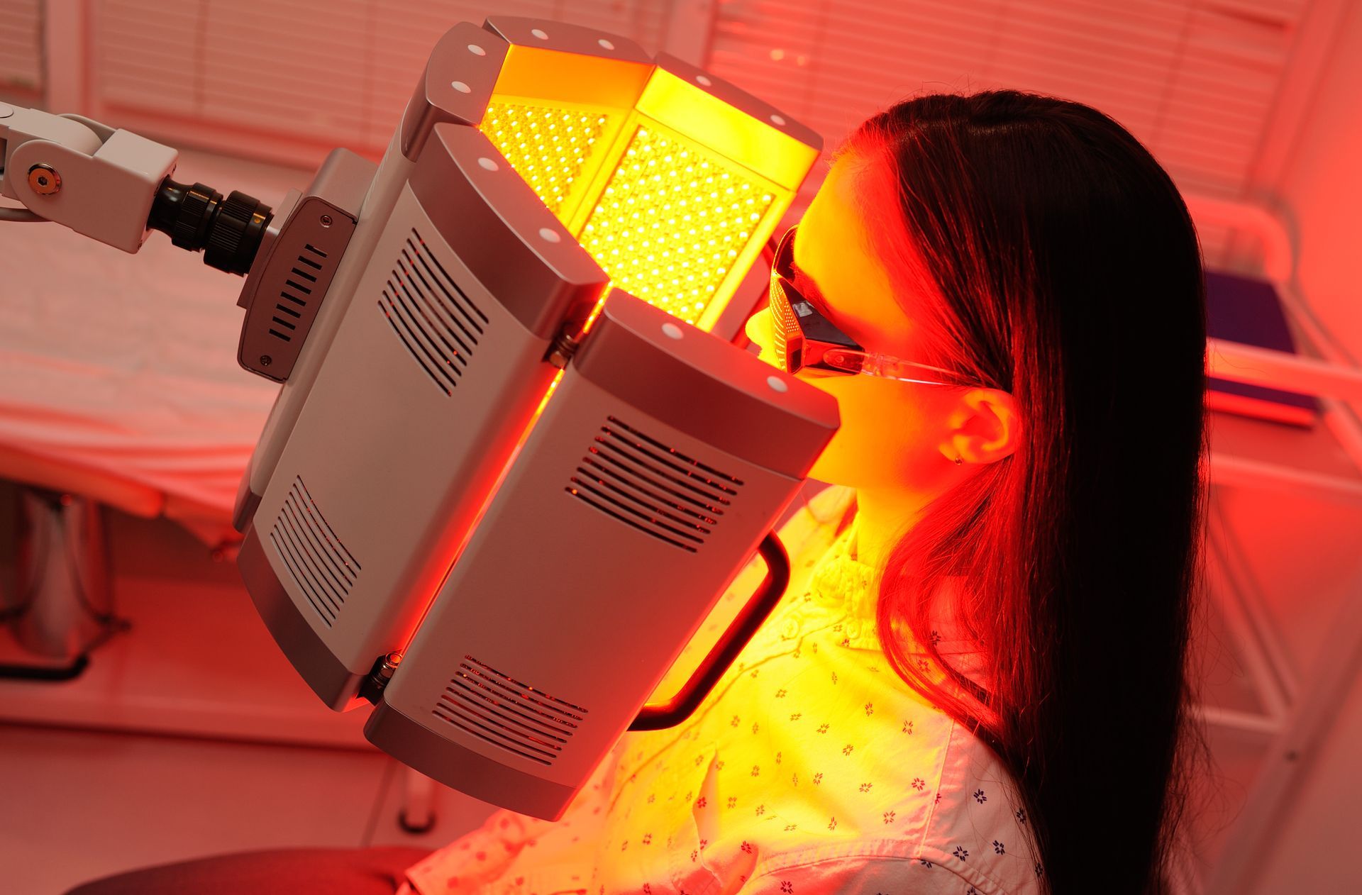 A woman is getting a red light treatment on her face