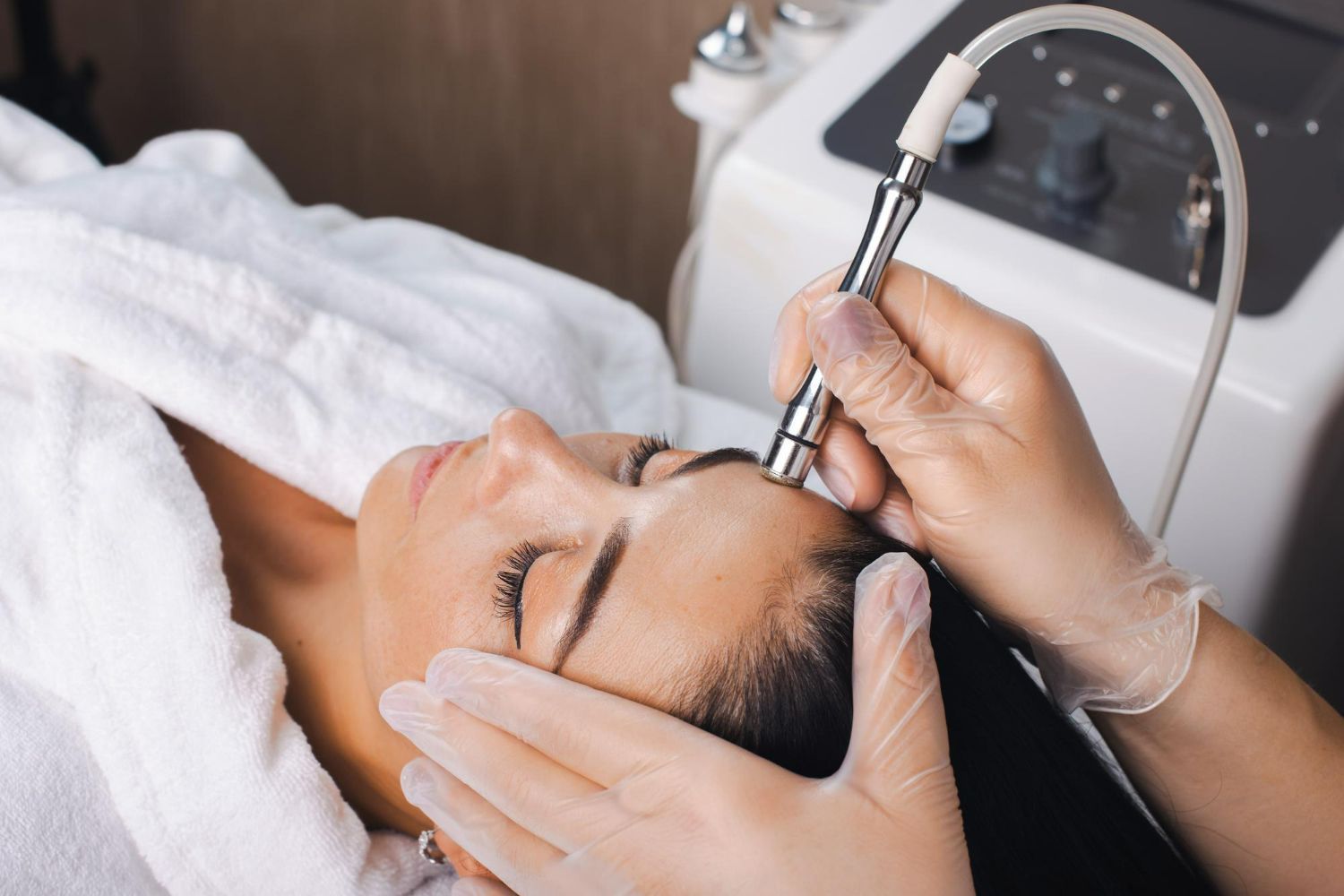Woman receiving a facial treatment with a machine.