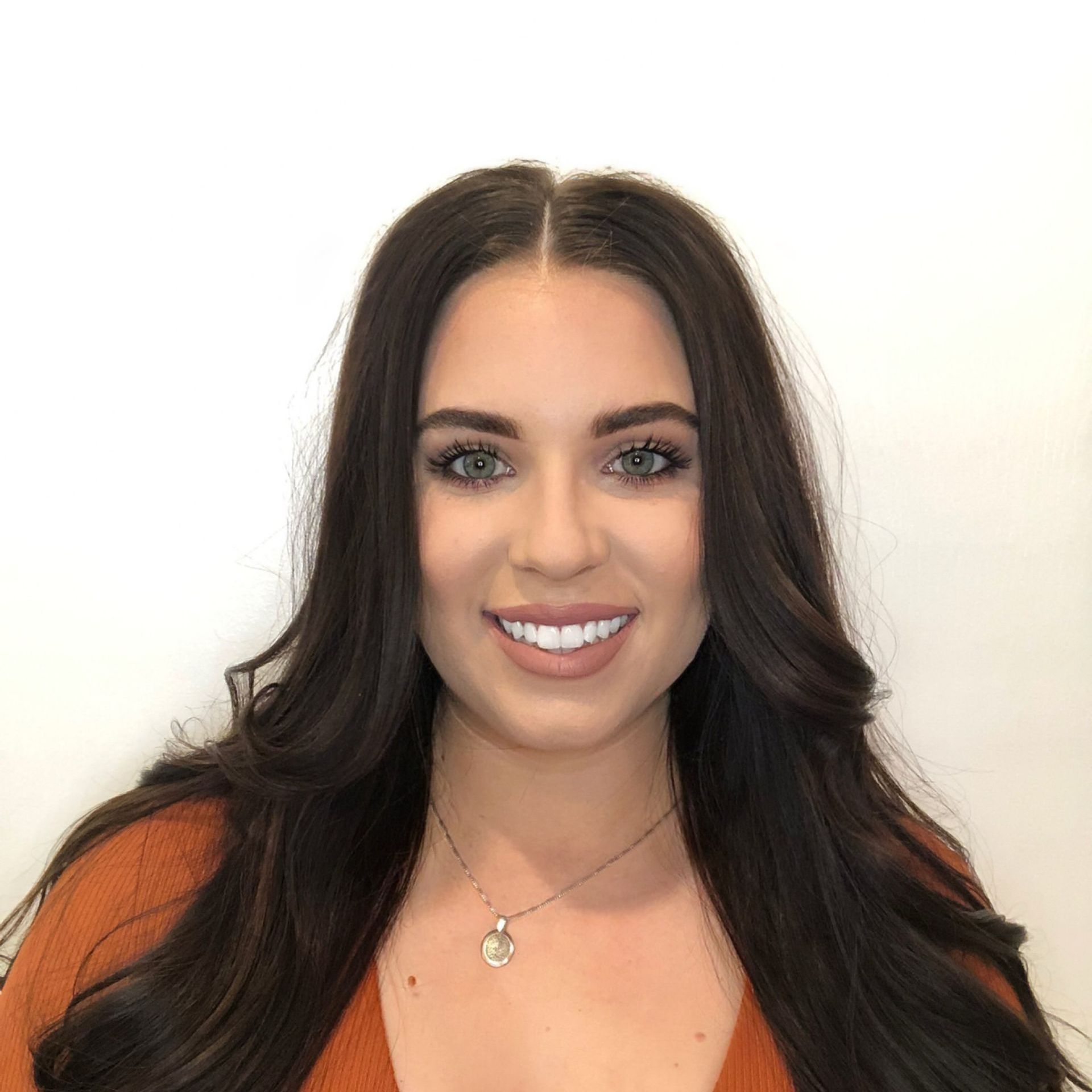 A woman in a white shirt is looking over her shoulder at the camera.