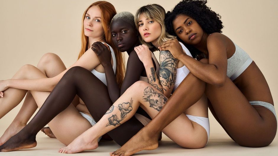 A group of women are sitting on the floor with their legs crossed.