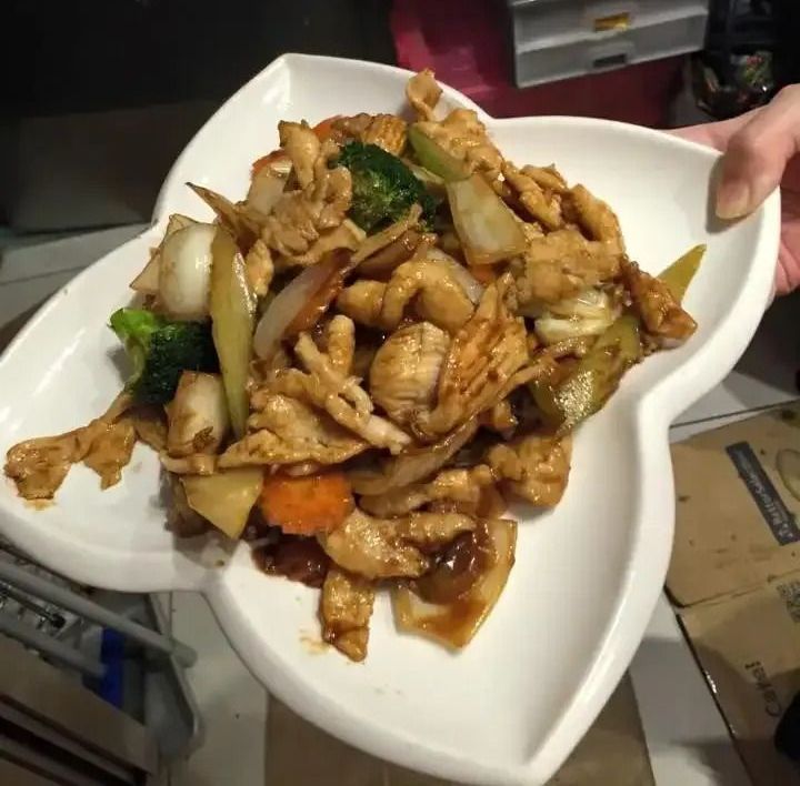 A Person is Holding a Plate of Chicken and Vegetables — Red Lantern Chinese Restaurant In Palmerston City, NT