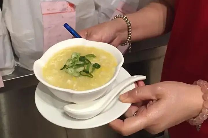 A Person is Holding a Bowl of Soup With a Spoon on a Saucer — Red Lantern Chinese Restaurant In Palmerston City, NT