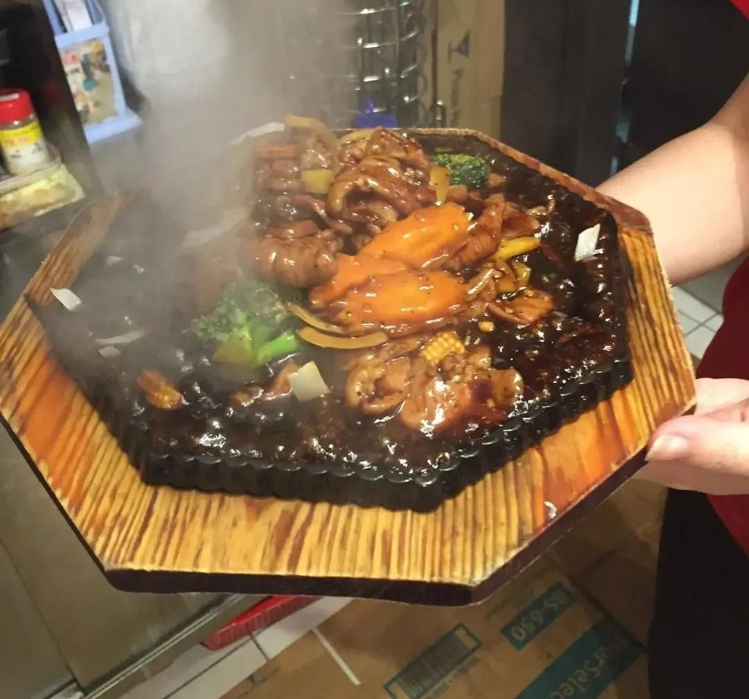 A Person is Holding a Plate of Food With Steam Coming Out of It — Red Lantern Chinese Restaurant In Palmerston City, NT