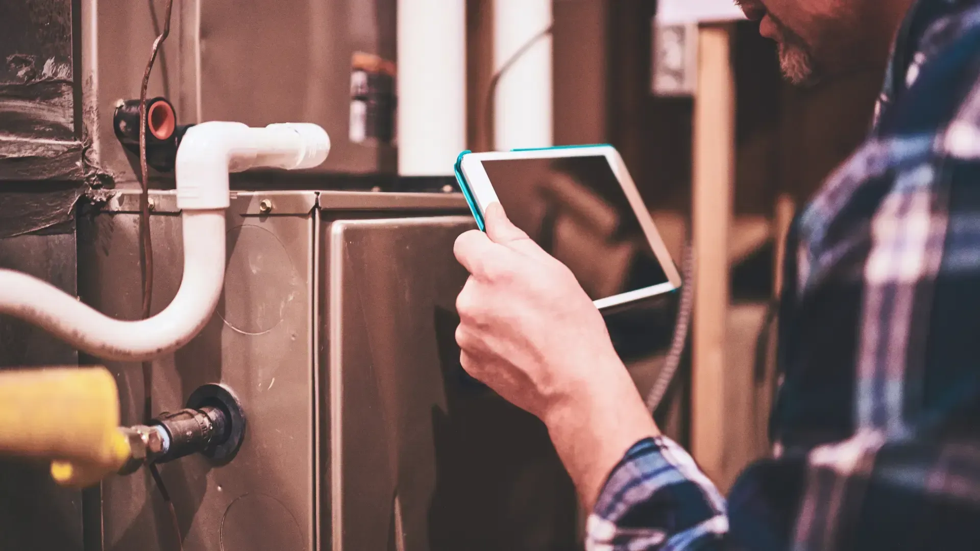 Man with tablet inspecting HVAC system.