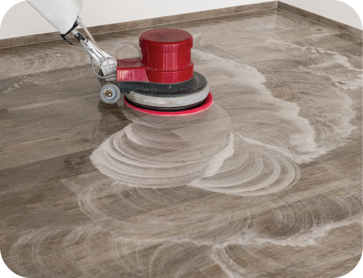 A person is cleaning a wooden floor with a machine.