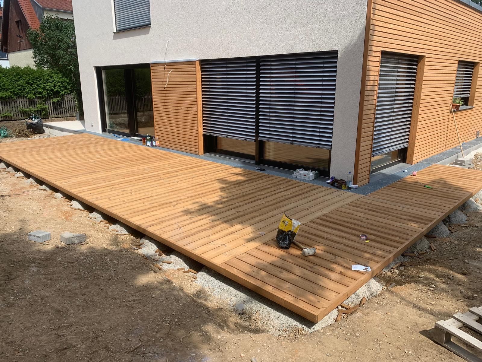 Vor einem Haus wird eine Holzterrasse gebaut.