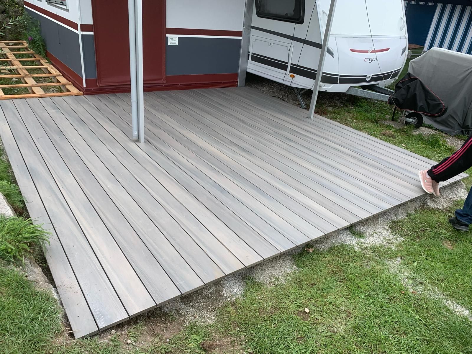 Eine Person steht auf einem Holzdeck neben einem Anhänger.