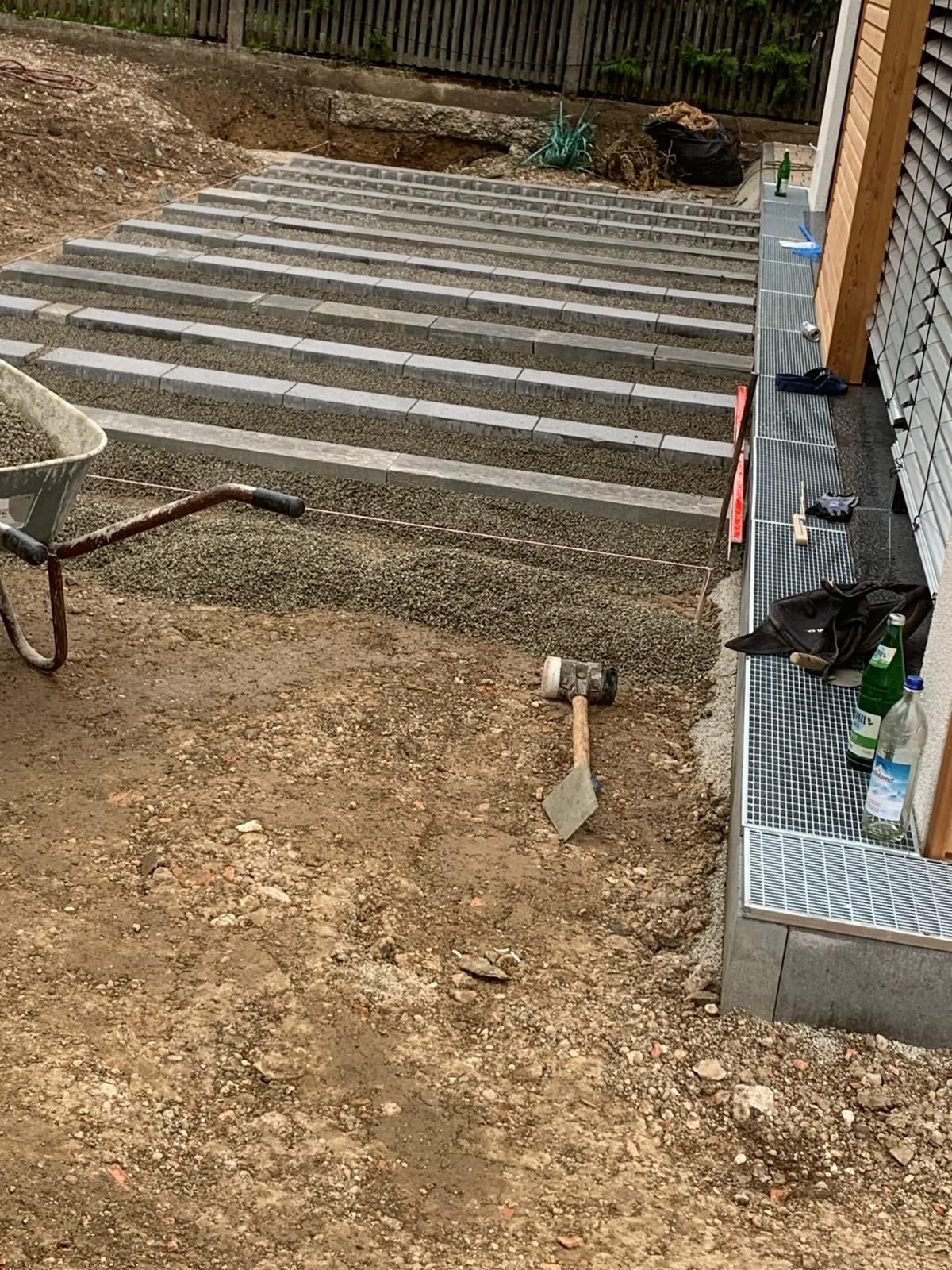 Auf dem Boden steht eine Schubkarre, daneben Hammer und Schaufel.