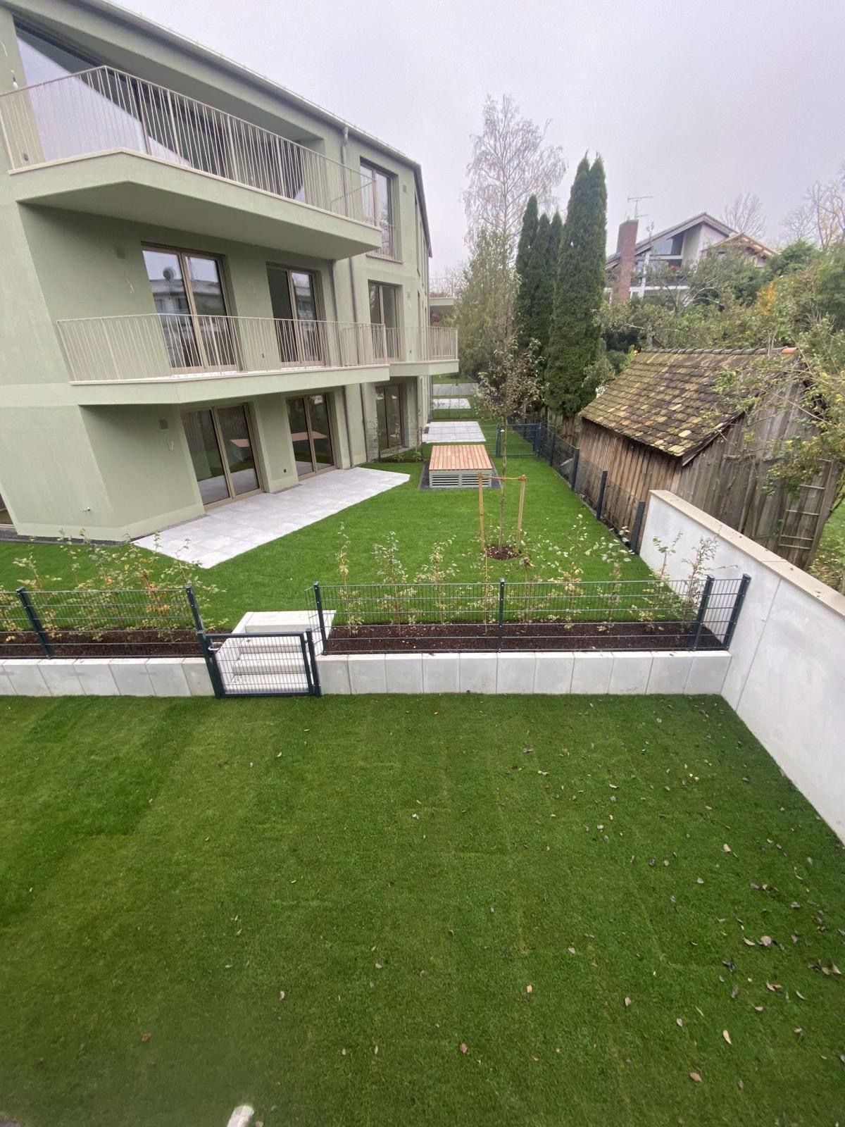 Vor einem Gebäude befindet sich eine große Rasenfläche.