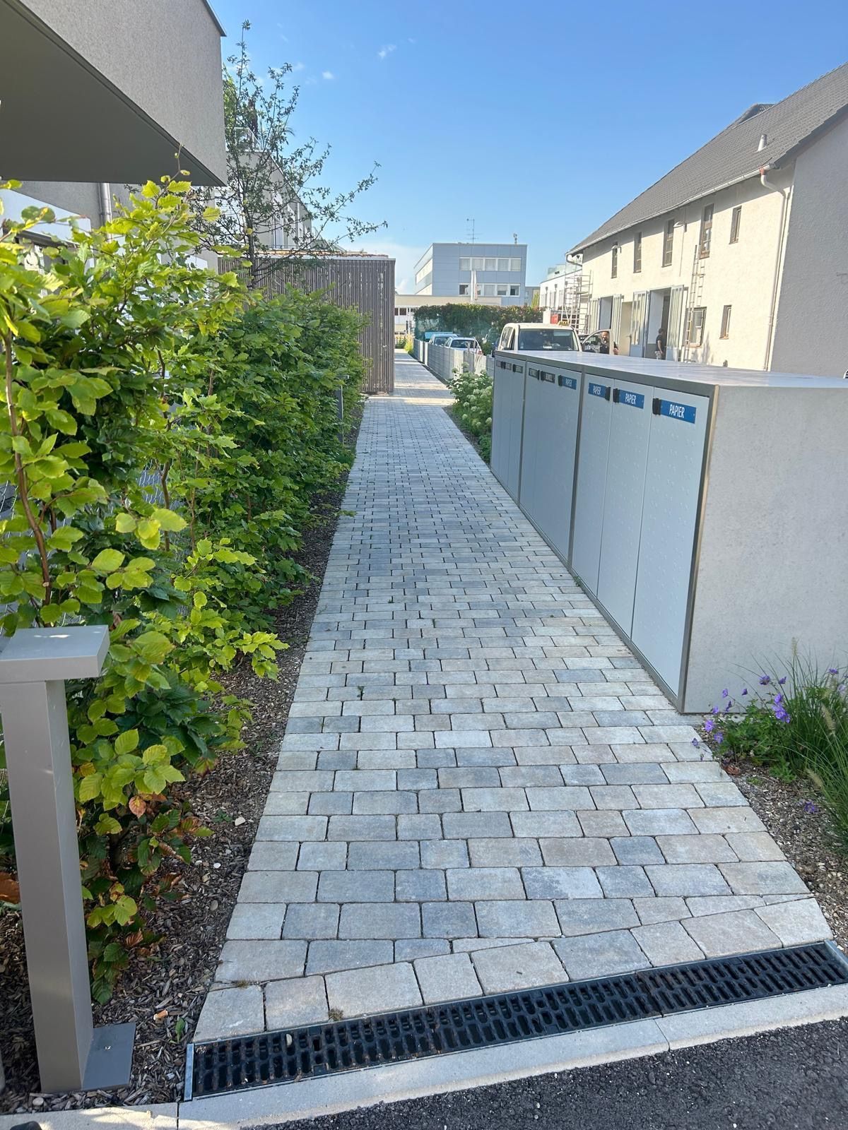 Ein gemauerter Gehweg, der zu einem Gebäude in einem Wohngebiet führt.