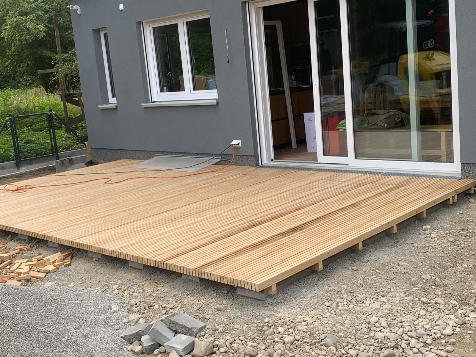 Vor einem Haus wird eine Holzterrasse gebaut.