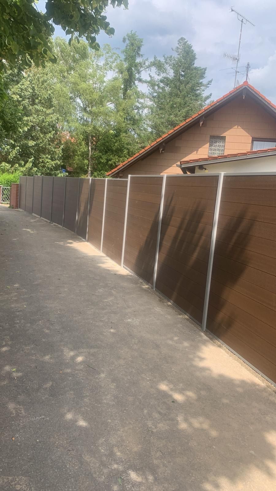 Neben einem Haus steht am Straßenrand ein Zaun.