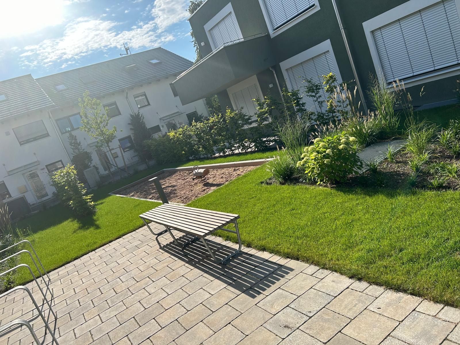 Eine Terrasse mit einer Bank und Stühlen vor einem Gebäude.