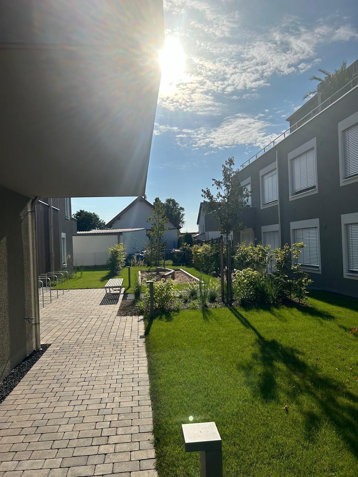 Ein gepflasterter Gehweg führt zu einem Gebäude mit einem üppigen grünen Rasen.