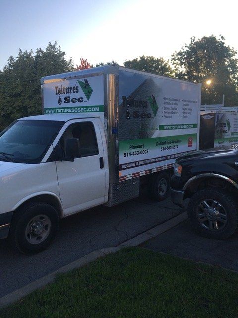 Un camion blanc avec une flèche verte sur le côté est garé sur le bord de la route