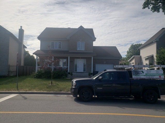 Un camion noir est garé devant une maison
