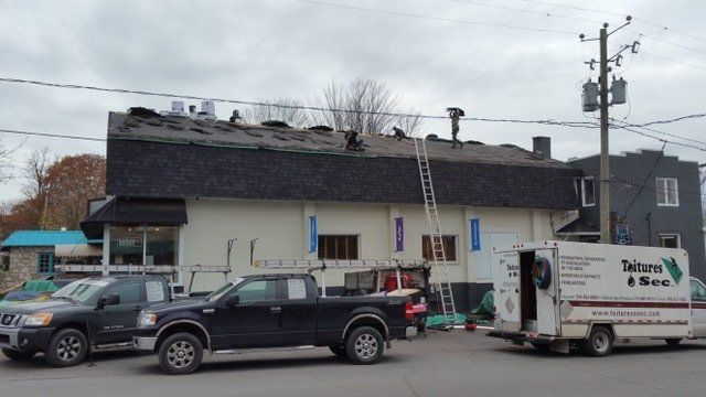 Deux camions sont garés devant un bâtiment avec une fourgonnette tétra devant lui