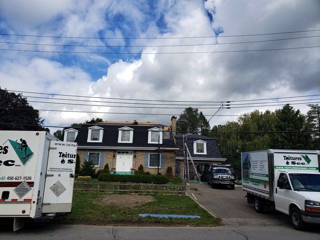 Deux camions sont garés devant une maison en cours de rénovation