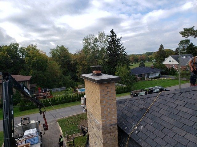 Un homme se tient debout sur un toit à côté d'une cheminée.