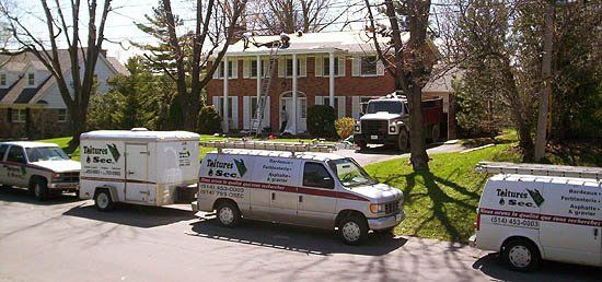 Trois camionnettes sont garées sur le bord de la route devant une maison.