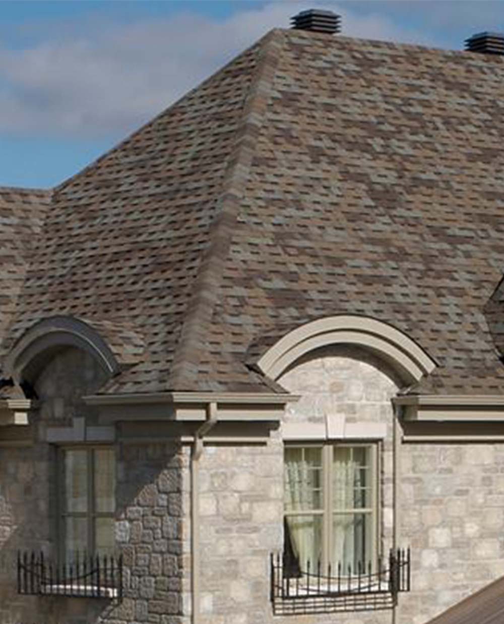 Une maison avec un toit brun et des fenêtres cintrées