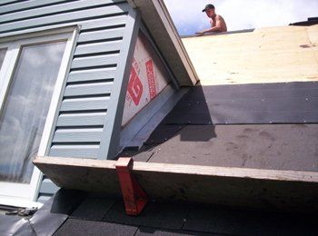 Un homme travaille sur le toit d'une maison