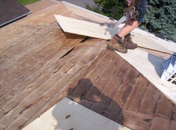 Une personne coupe un morceau de bois sur un toit