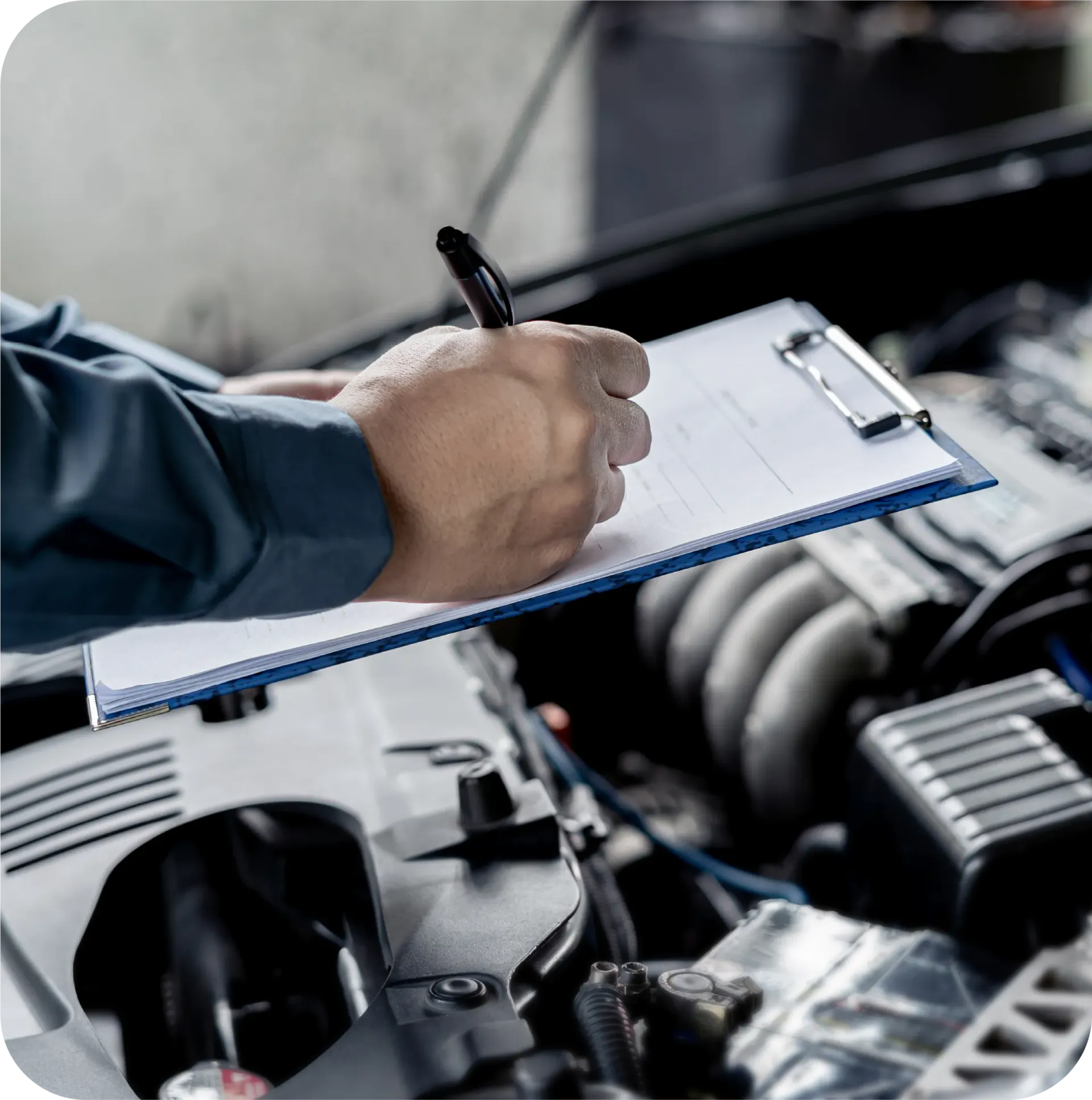 A man is writing on a clipboard in front of a car engine
